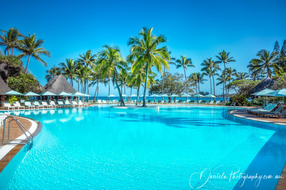 The stunning blue water pool at a resort on the beach in New Caledonia